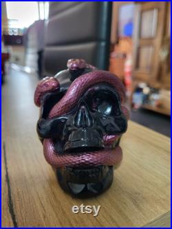 Une tête de mort avec un serpent qui sort de son orbite en s'enroulant autour de son crâne Une tête de mort avec un serpent qui sort de son orbite en s'enroulant autour de son crâne
