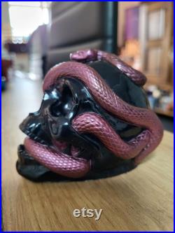 Une tête de mort avec un serpent qui sort de son orbite en s'enroulant autour de son crâne Une tête de mort avec un serpent qui sort de son orbite en s'enroulant autour de son crâne